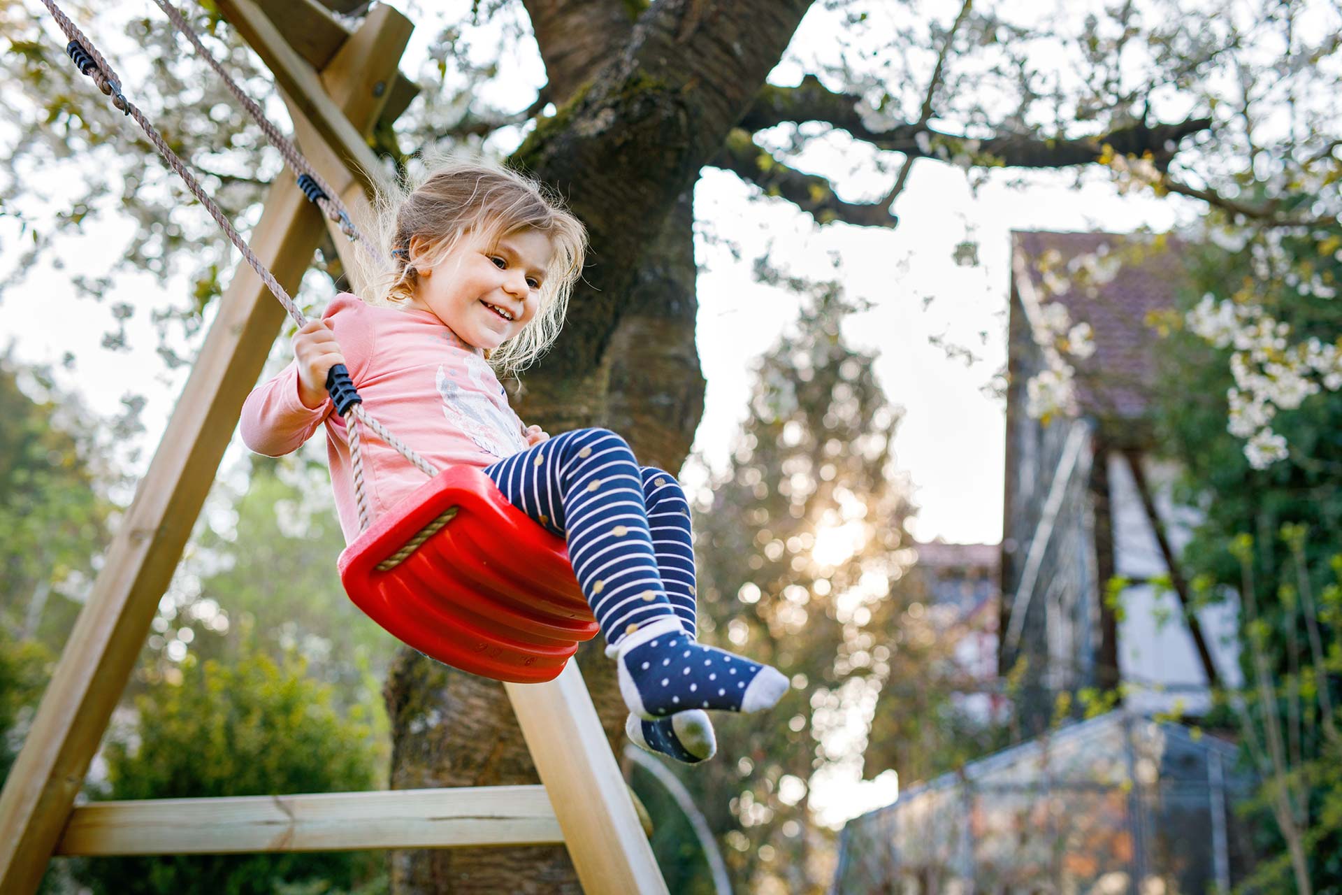 Kinderspielgeräte für Spiel und Spaß im Garten Mädchen schaukelt im Garten